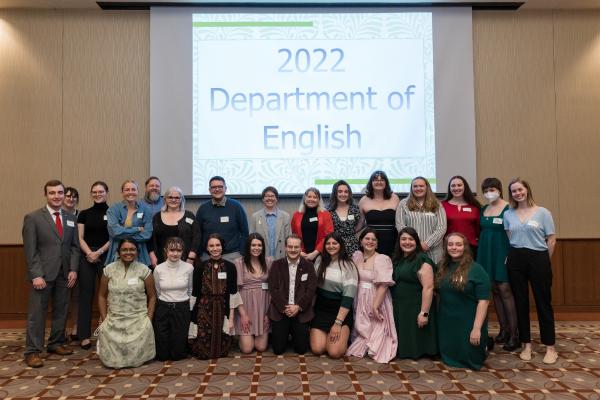 Several students gathered in front of a screen that reads 2022 Department of English